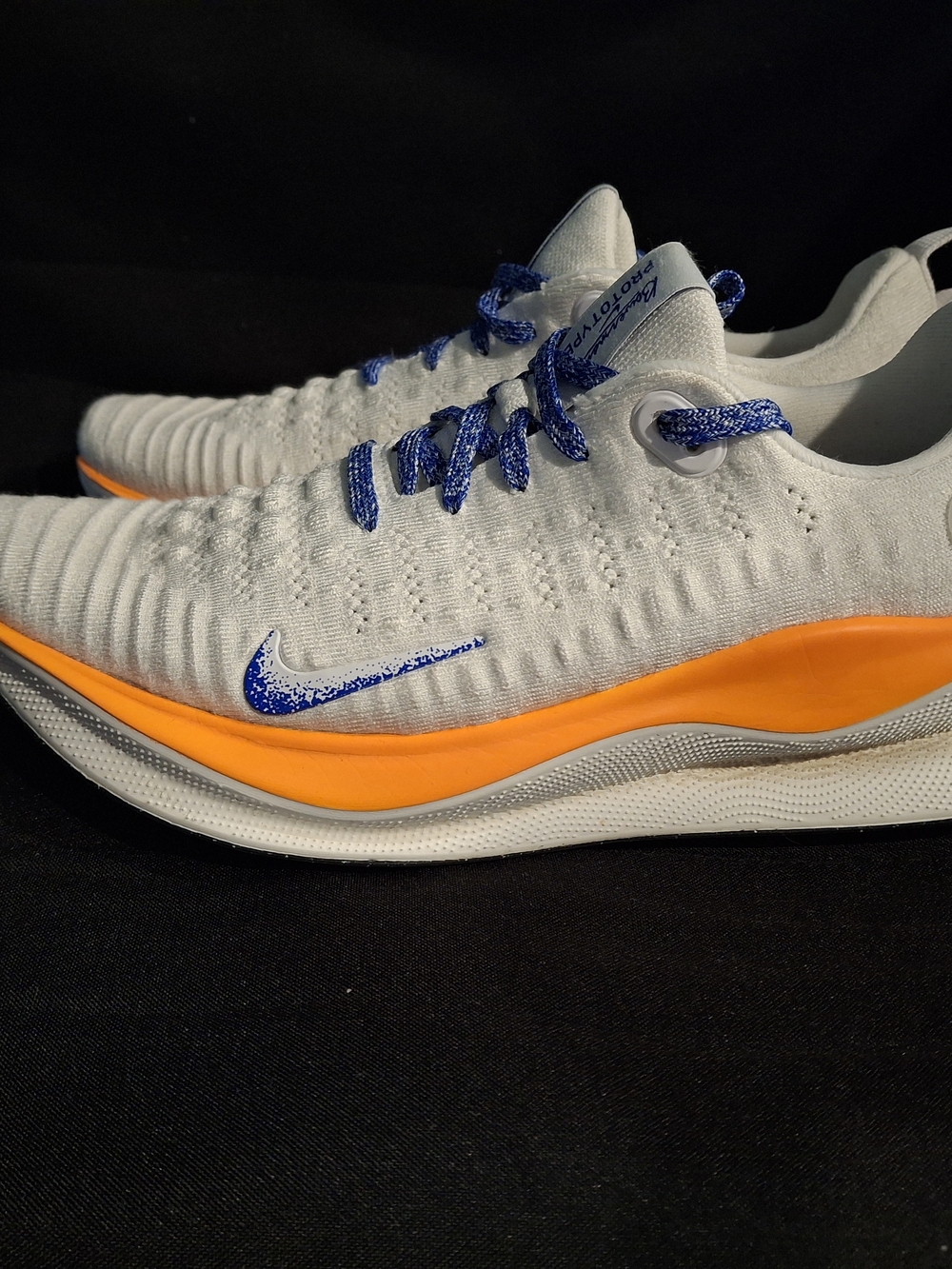 Nike White Flyknit Trainers with Orange Midsole and Blue Accents